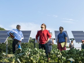 Image of a community standing with solar panels