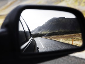 The rear view mirror of a car driving in the countryside