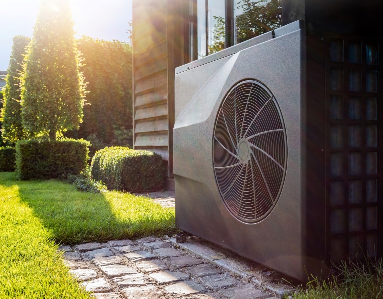 A grey heat pump in a homeowner's garden