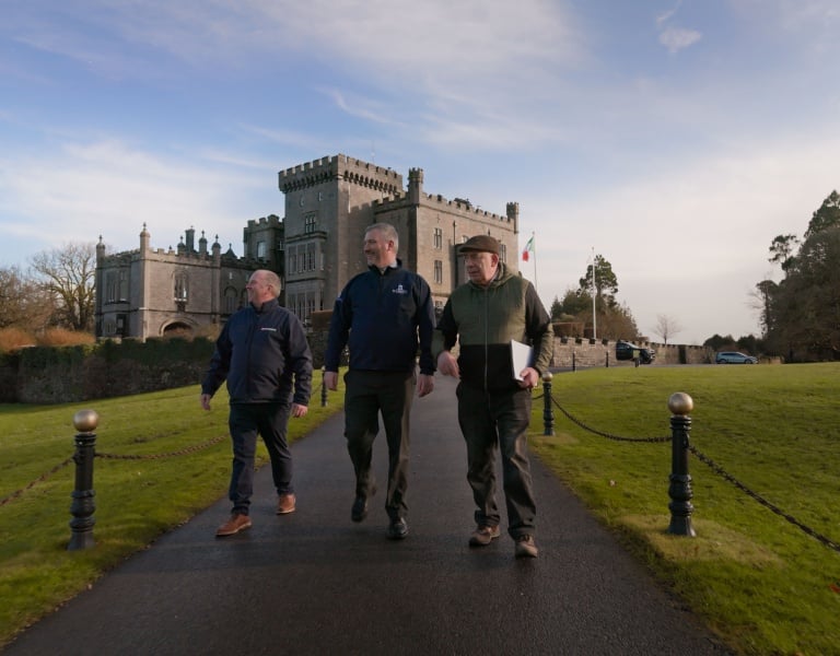 Three men walking with Markree Castle Hotel in the background.