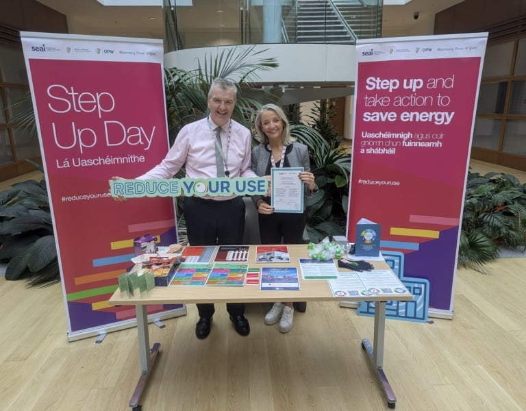 Two people standing at an IBTS stand holding a sign saying 'Reduce Your Use'