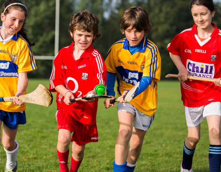 4 children playing GAA with a sliotar that says Better Energy