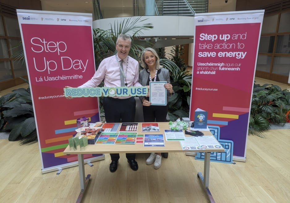 Two people standing at an IBTS stand holding a sign saying 'Reduce Your Use'