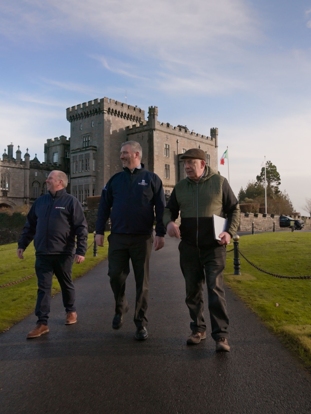 Three men walking with Markree Castle Hotel in the background.