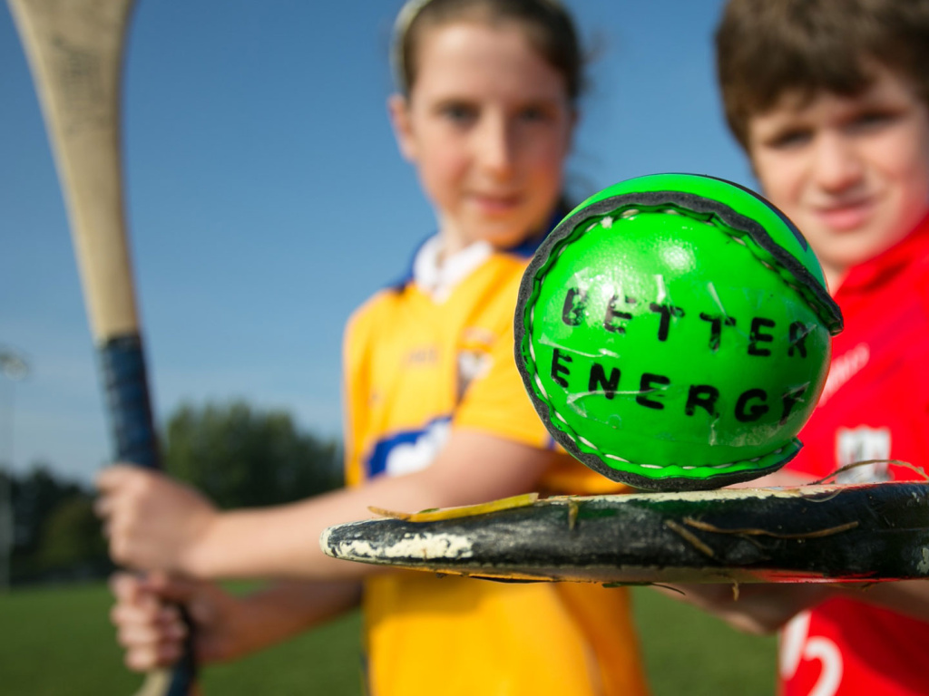 2 children playing GAA with a sliotar that says Better Energy