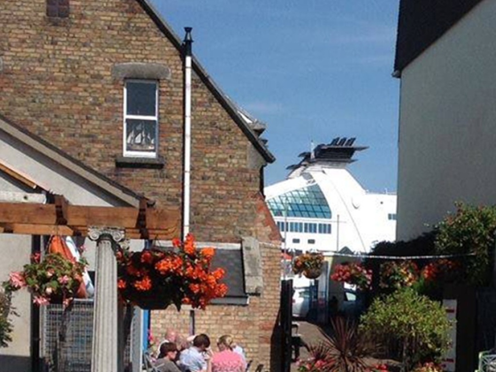 The exterior of a cafe with flowers, seats and the sky