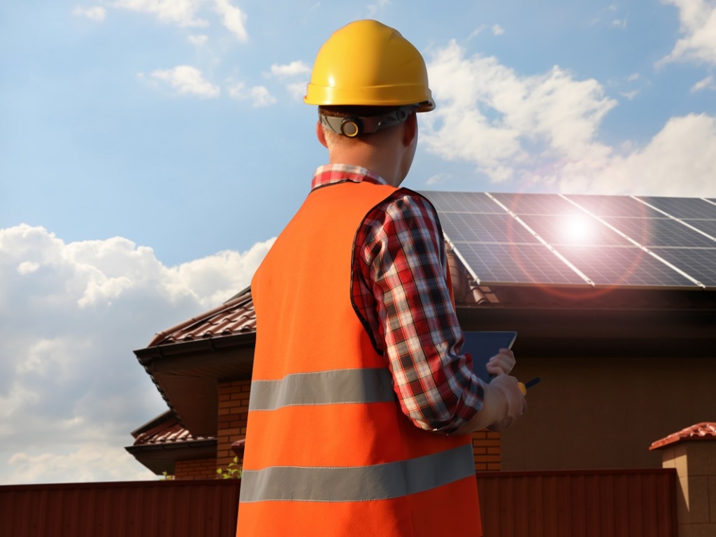 Contractor in a hard hat installing solar panels